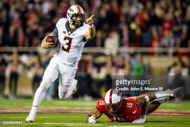 Quarterback Spencer Sanders of the Oklahoma State Cowboys runs past defensive lineman Tyree Wilson during the first half of the college football game...