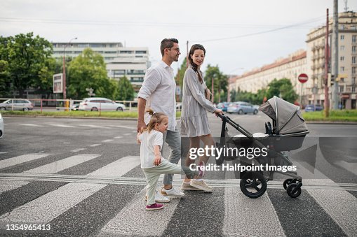 Happy young family with baby in stroller and little daughter on zebra crossing outdoors in town. Happy young family with baby in stroller and little daughter on zebra crossing outdoors in town.