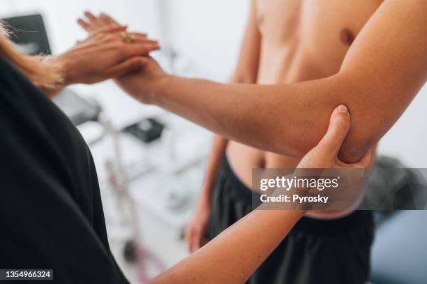 physiotherapist examining patient elbow - osteopathie stockfoto's en -beelden