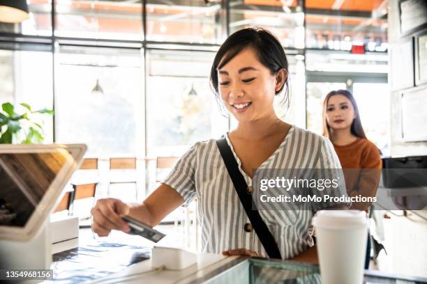 young woman using credit card reader at coffee shop counter - mostrador de tienda para pagar fotografías e imágenes de stock