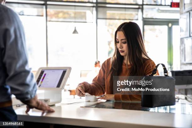 young woman using credit card reader at coffee shop counter - counter stand stock-fotos und bilder