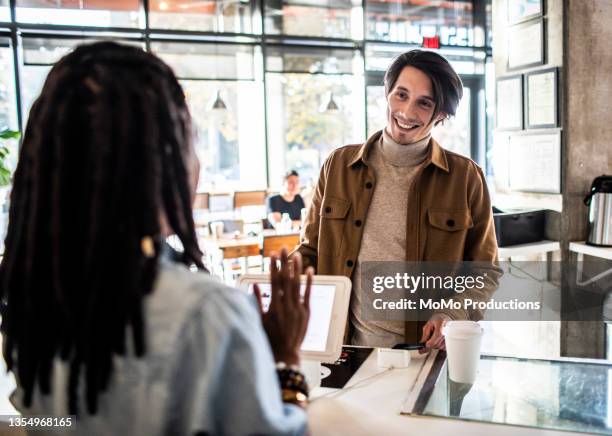 young man using credit card reader at coffee shop counter - two executive man coffee shop stockfoto's en -beelden