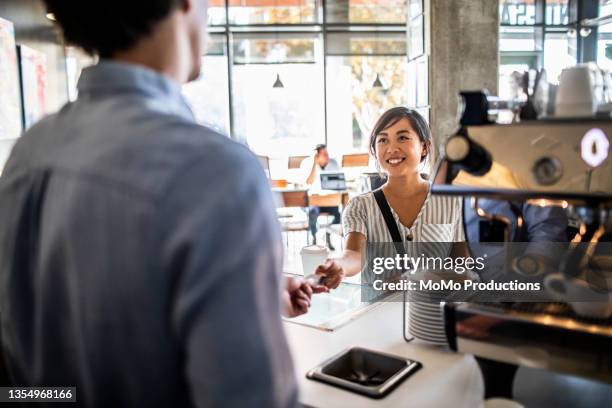 young woman paying for coffee with credit card - coffee bar stock-fotos und bilder