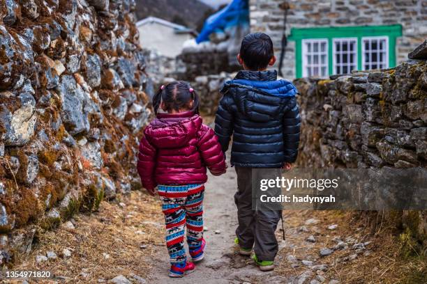 boy and girl walking in a village in mount everest national park, nepal - sherpa nepal stock pictures, royalty-free photos & images