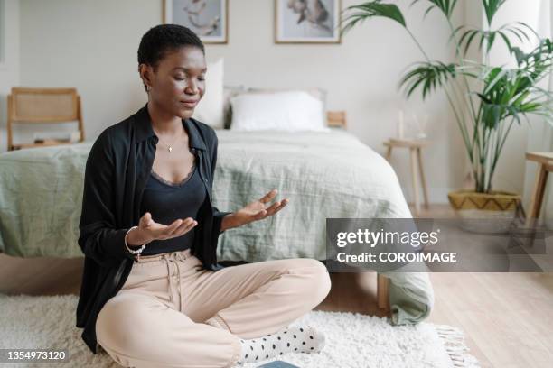 relaxed woman sitting on the floor practicing meditation after reading book. - spiritueel stockfoto's en -beelden