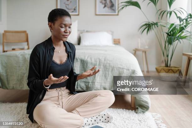 relaxed woman sitting on the floor practicing meditation after reading book. - meditation stock pictures, royalty-free photos & images