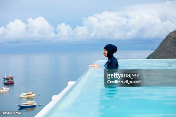 asiatische muslimische frau im infinity-pool - muslim woman beach stock-fotos und bilder