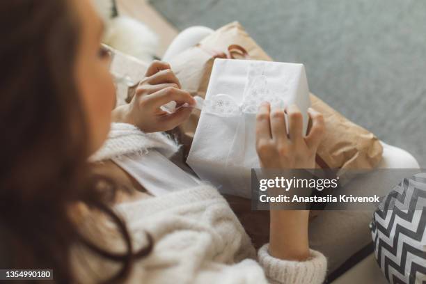 woman opening christmas presents near fir tree at cozy decorated home. - geschenk auspacken stock-fotos und bilder