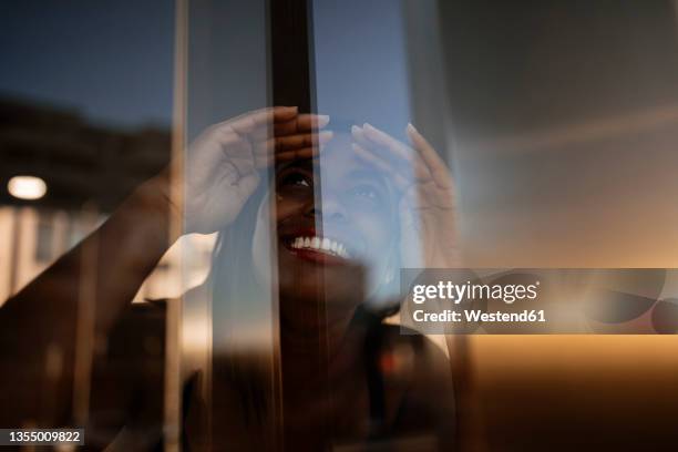 smiling woman shielding eyes while looking through window - train window stock pictures, royalty-free photos & images