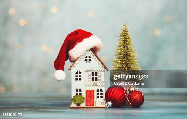 house with santa hat and christmas tree and holiday decorations. home for the holidays theme - christmas sayings stock pictures, royalty-free photos & images