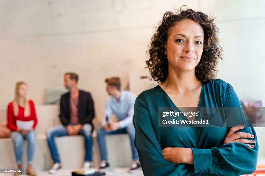 Smiling businesswoman with arms crossed at workplace