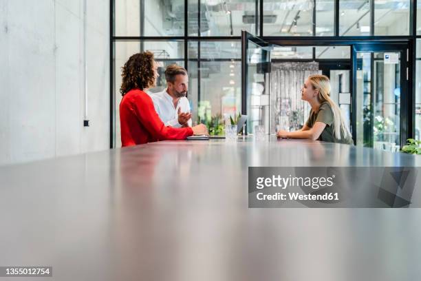 recruiters having discussion with candidate at conference table - colloquio di lavoro foto e immagini stock