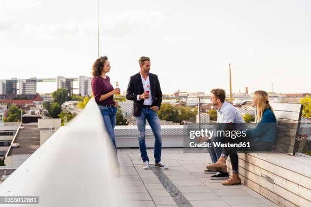 colleagues holding drinks at building rooftop - feierabend stock-fotos und bilder