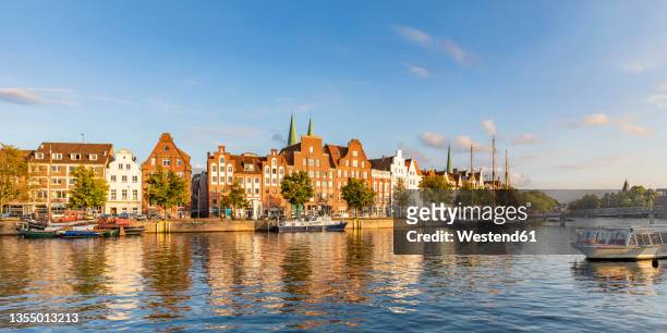 germany, schleswig-holstein, lubeck, panoramic view of river trave canal with historic townhouses in background - lübeck foto e immagini stock