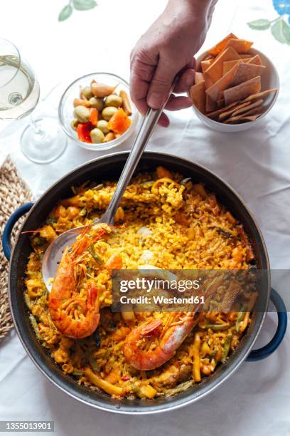hand of senior woman taking seafood paella with spatula - spanish food stock pictures, royalty-free photos & images