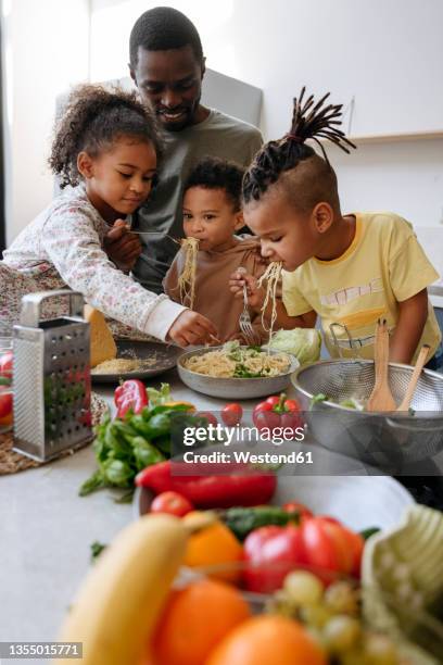 family enjoying spaghetti in kitchen at home - female eating chili bildbanksfoton och bilder