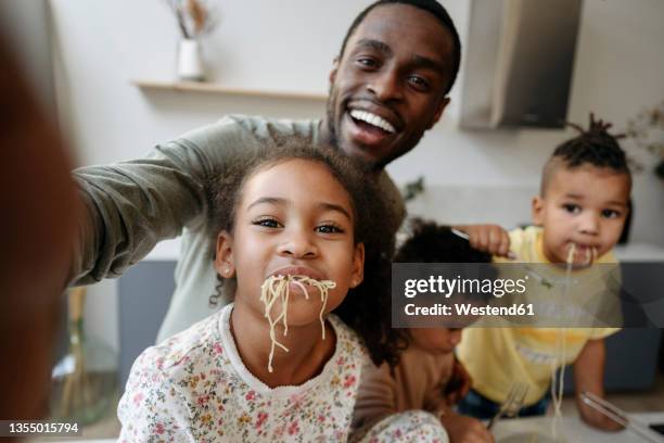 happy man taking selfie with daughter and sons having spaghetti in kitchen - family selfie stock pictures, royalty-free photos & images