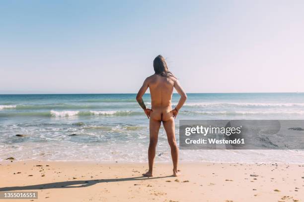 naked man with hand on hip at beach - beach bum stock pictures, royalty-free photos & images