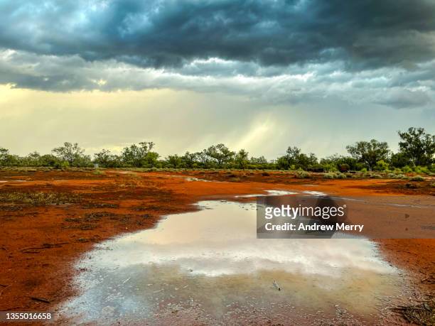 dark storm clouds, rain water on red dirt farm australia - australia summer reflection stock-fotos und bilder