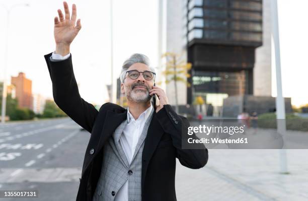 businessman with hand raised hailing taxi on road - taxi españa stockfoto's en -beelden