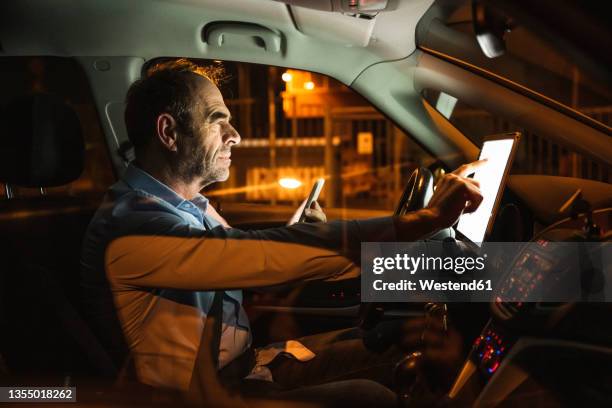 businessman using tablet pc in car at night - fachmann auto smartphone stock-fotos und bilder