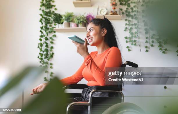 smiling disabled woman talking on mobile phone at home - latin american and hispanic ethnicity on phone stock pictures, royalty-free photos & images