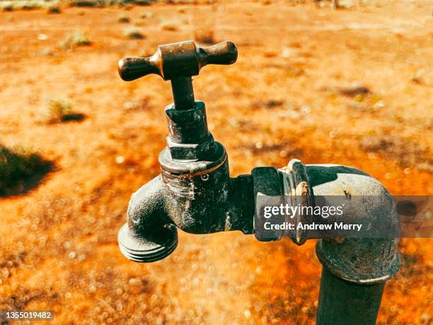 outdoor water tap faucet, desert dirt, orange background, australia - broken pipe stockfoto's en -beelden