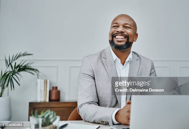 shot of a mature businessman using a laptop in a modern office - man business looking up stockfoto's en -beelden