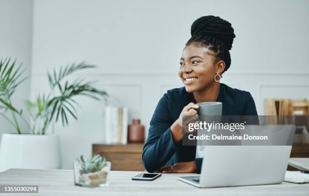 shot of a young businesswoman using a laptop and having coffee in a modern office - business desk imagens e fotografias de stock