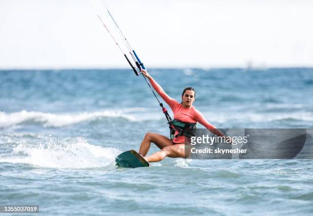 young woman enjoying in kiteboarding during summer day at sea. - kite surfing stock pictures, royalty-free photos & images