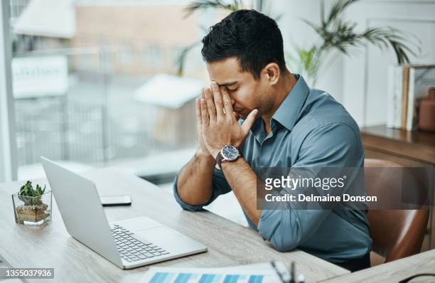 foto de un joven empresario que parece estresado mientras trabaja en una oficina moderna - frustración fotografías e imágenes de stock