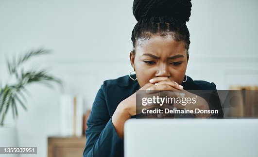 Shot of a young businesswoman frowning while using a laptop in a modern office Shot of a young businesswoman frowning while using a laptop in a modern office