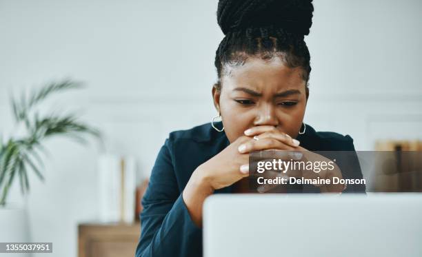 tiro de uma jovem empresária franzindo a testa enquanto usava um laptop em um escritório moderno - confusão - fotografias e filmes do acervo