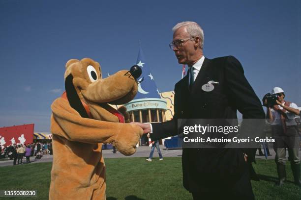 Le parc Euro Disneyland un an avant son ouverture : La mascotte Pluto serrant la main à Robert Fitzpatrick.