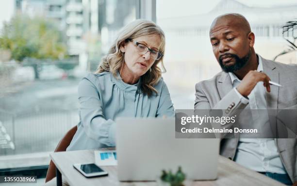 shot of a businessman and businesswoman using a laptop together in a modern office - serious meeting stock pictures, royalty-free photos & images