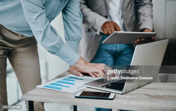shot of a businessman and businesswoman using a laptop and digital tablet during a meeting in a modern office - auditoria imagens e fotografias de stock