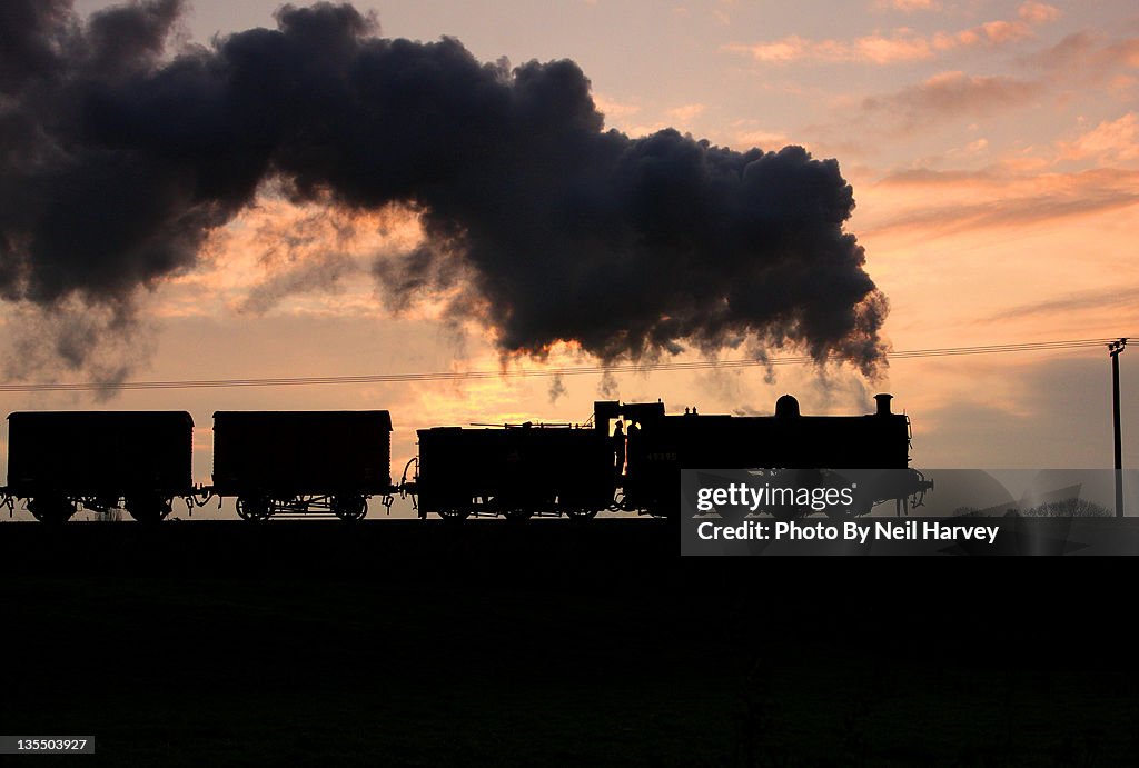 Backlit of train an smoke against dusk