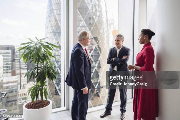 financial advisors standing and talking in modern office - norman foster gebouw stockfoto's en -beelden