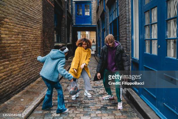 three happy friends dancing together in the city - three people dancing stock pictures, royalty-free photos & images