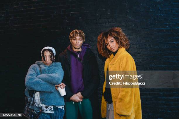 portrait of three hip friends against a black bricks wall in the city - woman rap stock pictures, royalty-free photos & images