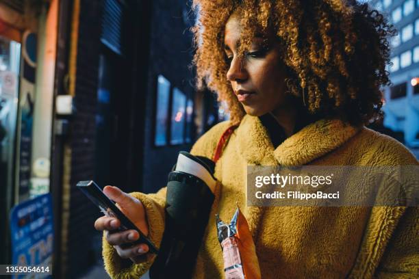 hip young adult woman using her smartphone in the city - yellow shoe stock pictures, royalty-free photos & images