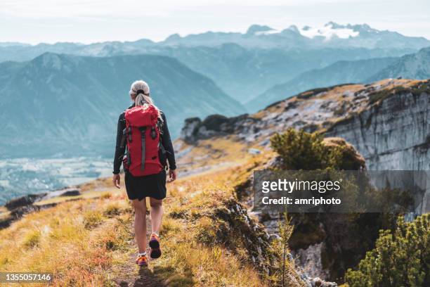 one woman hiking along mountain ridge, rear view - austria mountains stock pictures, royalty-free photos & images