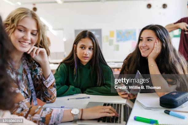 three friends working together on task during class - students talking stockfoto's en -beelden