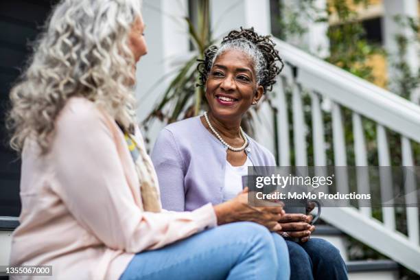 senior women having coffee in front of suburban home - best friends women fotografías e imágenes de stock