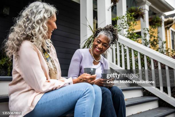 senior women having coffee in front of suburban home - buren stockfoto's en -beelden
