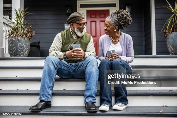 senior couple having coffee in front of suburban home - suburban lifestyles stock pictures, royalty-free photos & images