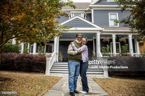 portrait of senior husband and wife in front of suburban home - couple lifestyle jean stock pictures, royalty-free photos & images