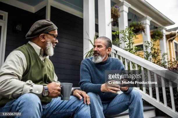 senior men having coffee in front of suburban home - hand on knee stock pictures, royalty-free photos & images