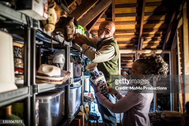 senior couple organizing items in home attic - huishoudelijk werk stockfoto's en -beelden