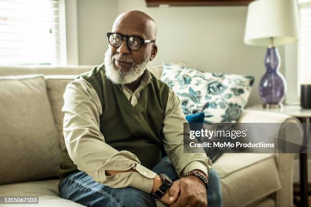 portrait of senior man in living room of suburban home - esperar - fotografias e filmes do acervo